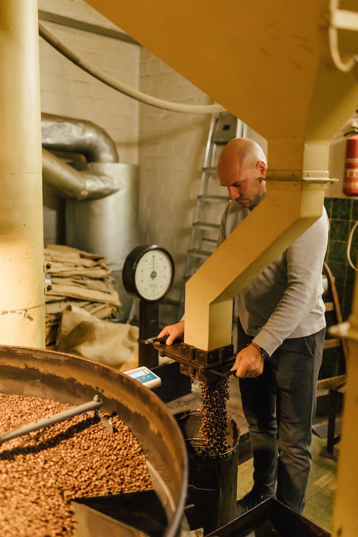 Kaffeeröster in der Kaffee Faensen Rösterei beim Befüllen der Trommelröstmaschine
